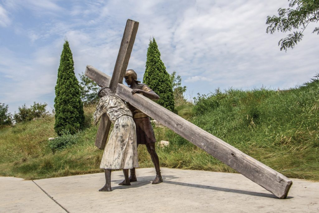 A statue of Jesus carrying the cross with a soldier beside Him