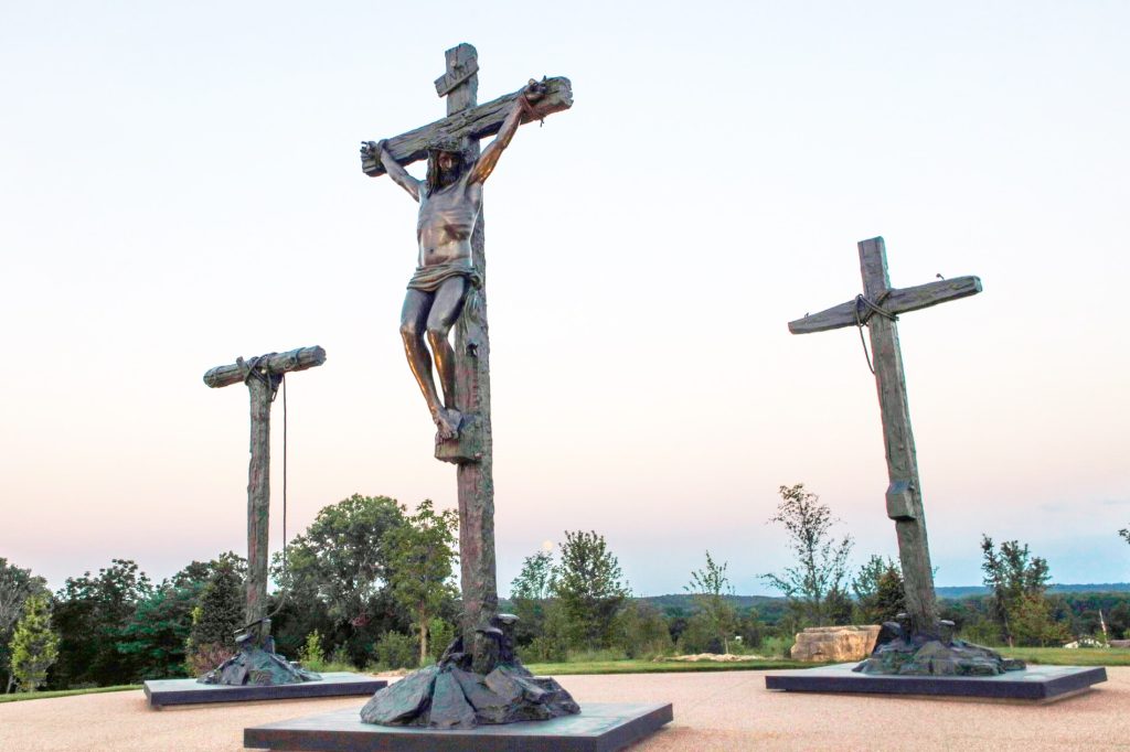 A statue of Jesus on the cross with two empty crosses beside Him